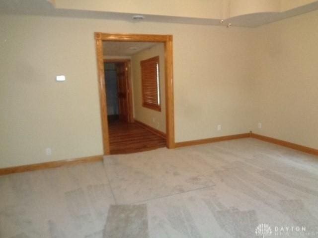 unfurnished room with light carpet and baseboards