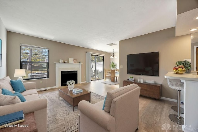 living room with visible vents, baseboards, light wood-style flooring, and a fireplace