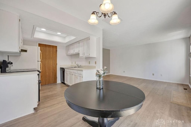 kitchen featuring light wood-type flooring, white cabinetry, light countertops, a raised ceiling, and dishwasher