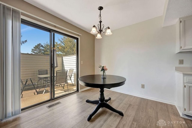 dining area with baseboards, visible vents, light wood finished floors, and a chandelier