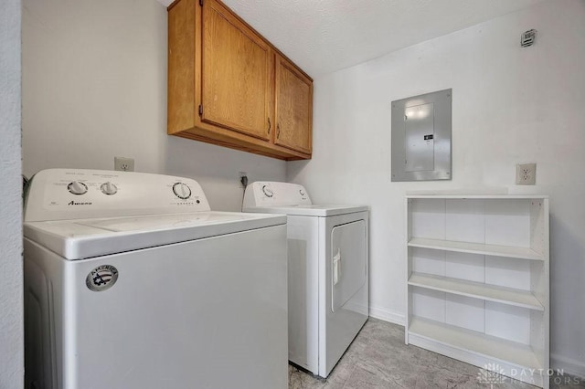 washroom with electric panel, a textured ceiling, washing machine and dryer, cabinet space, and baseboards