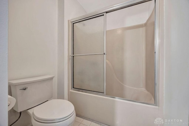 bathroom featuring tile patterned floors, toilet, and bath / shower combo with glass door