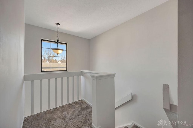 stairway with a textured ceiling and carpet