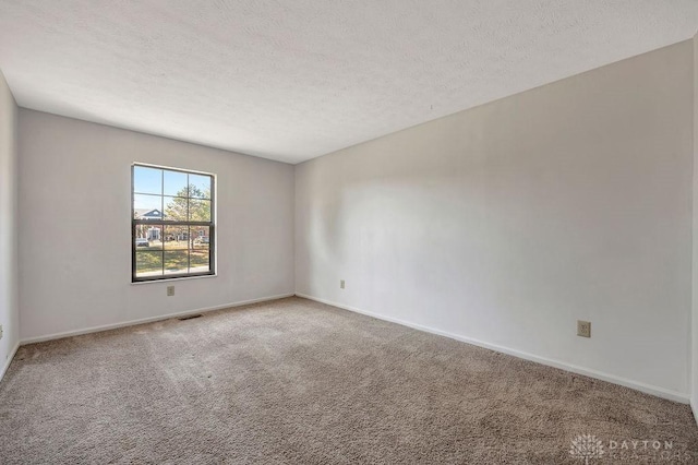 spare room with baseboards, carpet flooring, a textured ceiling, and visible vents