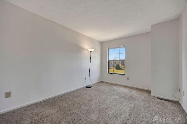 empty room featuring baseboards, visible vents, a textured ceiling, and carpet