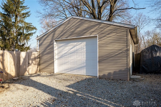 detached garage with gravel driveway and fence