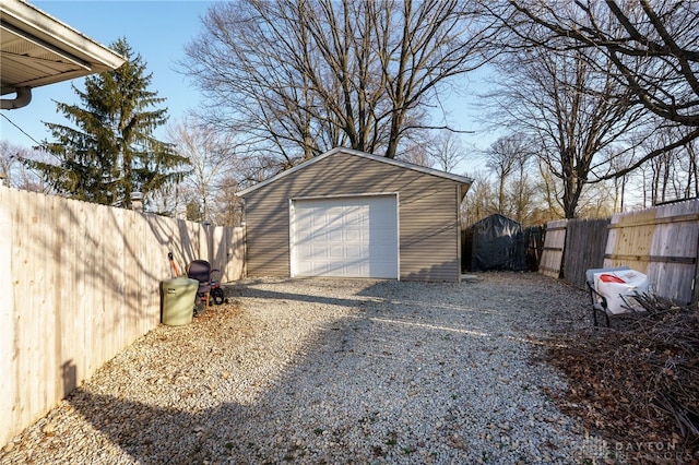 detached garage with gravel driveway and fence