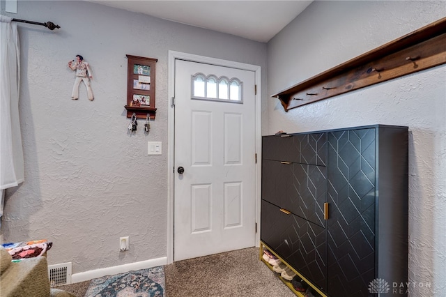 carpeted entrance foyer with visible vents and a textured wall