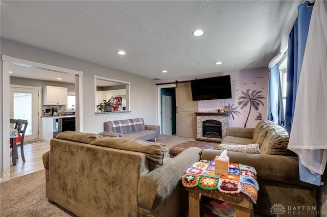 living room with a fireplace, a barn door, recessed lighting, and a textured ceiling