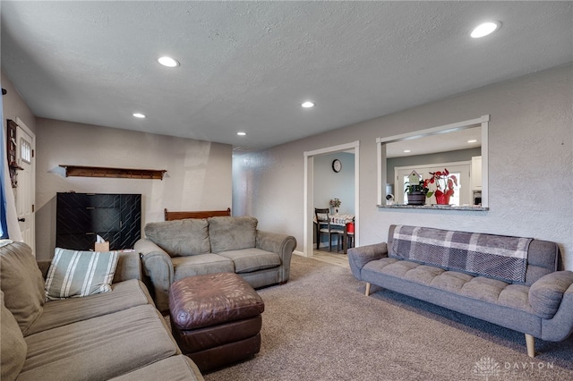 carpeted living area with recessed lighting, a textured ceiling, and a textured wall