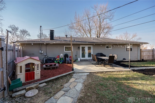 rear view of property with fence, french doors, a chimney, a yard, and a patio