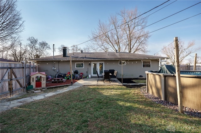 rear view of property featuring a patio area, a lawn, a fenced in pool, and fence