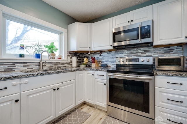 kitchen featuring dark stone counters, a toaster, a sink, decorative backsplash, and stainless steel appliances