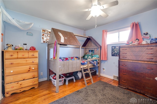 bedroom with visible vents, a ceiling fan, baseboards, and wood finished floors