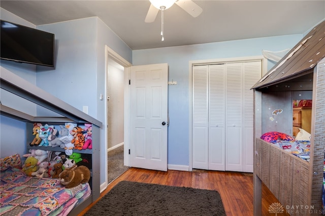 bedroom featuring a closet, baseboards, wood finished floors, and a ceiling fan