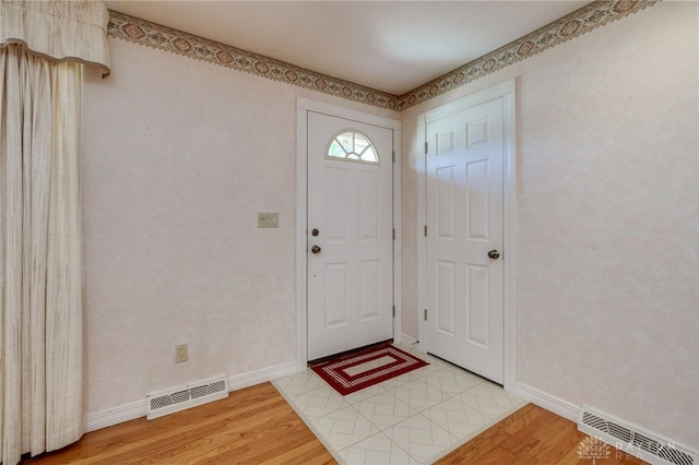 foyer featuring light wood finished floors, visible vents, and baseboards