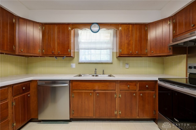 kitchen featuring under cabinet range hood, light countertops, appliances with stainless steel finishes, and a sink