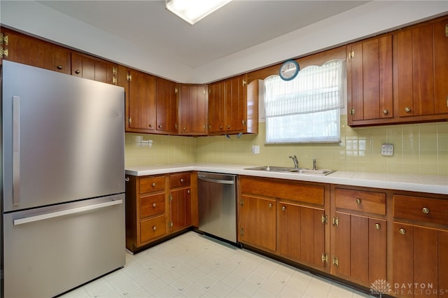 kitchen featuring backsplash, light floors, light countertops, appliances with stainless steel finishes, and a sink