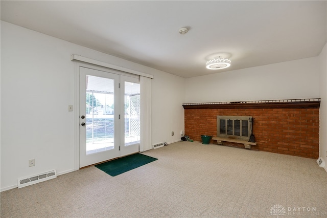 unfurnished living room featuring a brick fireplace, carpet flooring, baseboards, and visible vents