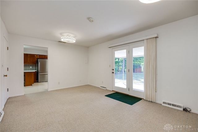 empty room featuring visible vents, light carpet, and baseboards