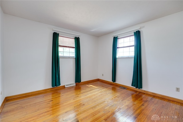 empty room featuring visible vents, plenty of natural light, and wood finished floors