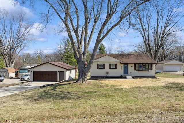 ranch-style house featuring an outbuilding, concrete driveway, a front lawn, and a detached garage