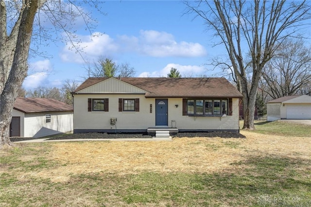 view of front of house with a detached garage, an outdoor structure, and a front lawn