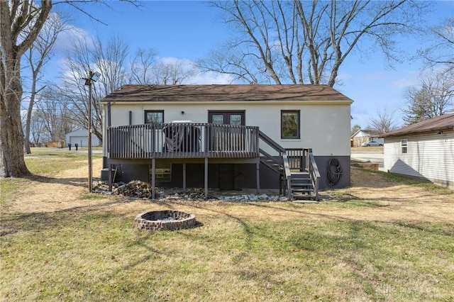 rear view of house featuring a deck, stairway, a yard, and a fire pit