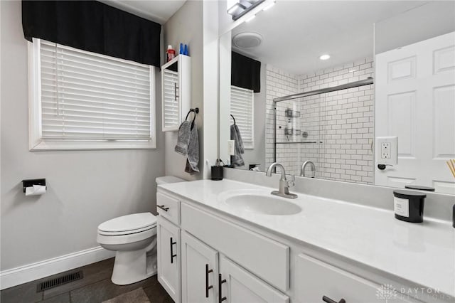 bathroom featuring visible vents, toilet, a stall shower, baseboards, and vanity