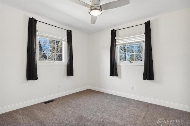 carpeted spare room with visible vents, a ceiling fan, and baseboards