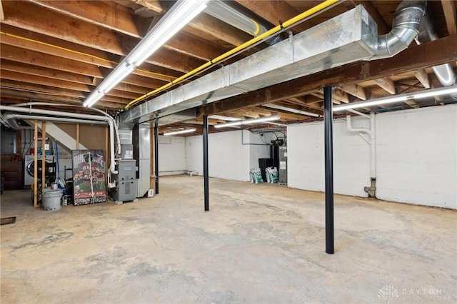 unfinished basement with heating unit, washer / dryer, and electric water heater