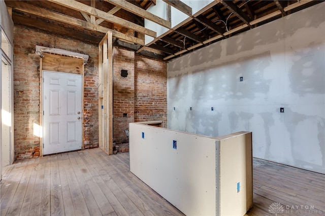 misc room featuring brick wall and hardwood / wood-style flooring