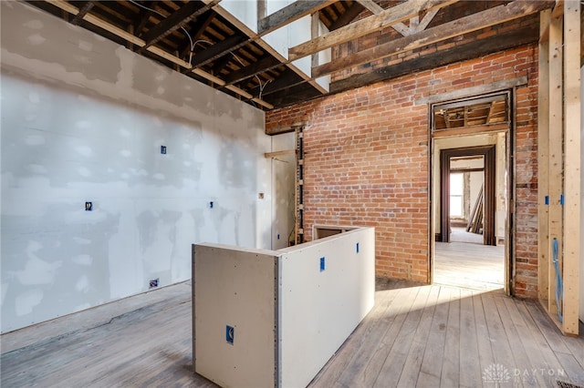 kitchen with wood-type flooring and brick wall