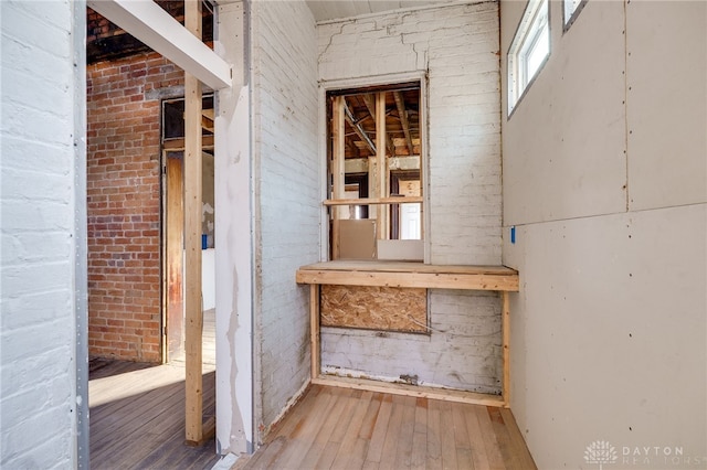 below grade area with wood-type flooring and brick wall