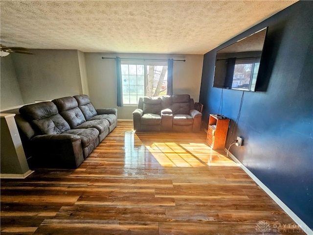 living area with baseboards, a textured ceiling, wood finished floors, and a ceiling fan