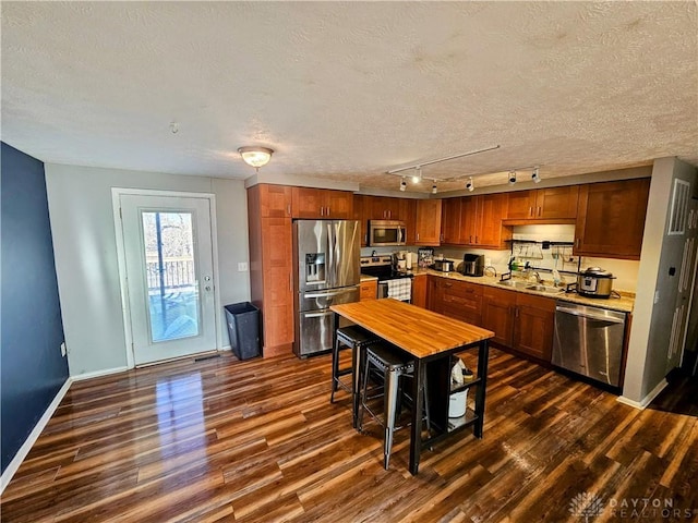 kitchen featuring baseboards, light countertops, appliances with stainless steel finishes, dark wood-style floors, and a textured ceiling