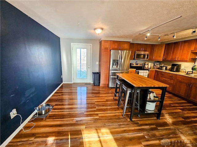 kitchen featuring brown cabinetry, appliances with stainless steel finishes, and dark wood-type flooring