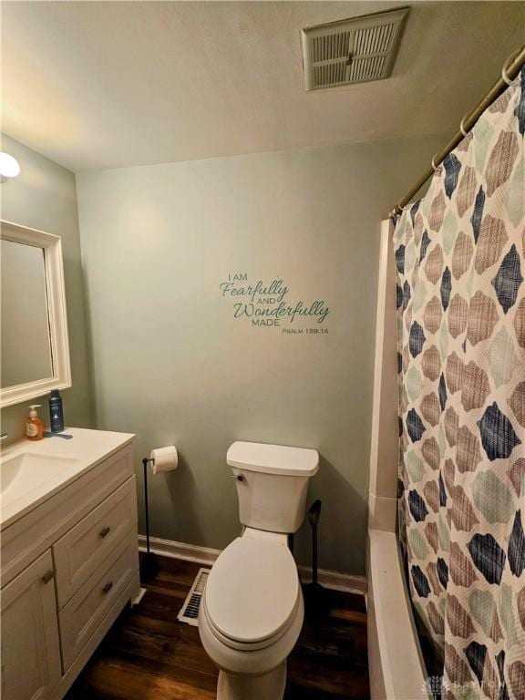 bathroom featuring visible vents, baseboards, toilet, wood finished floors, and vanity