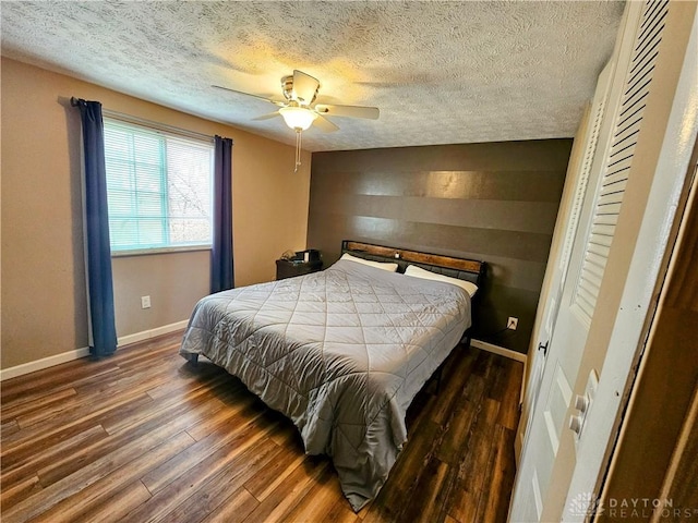 bedroom with a ceiling fan, wood finished floors, baseboards, and a textured ceiling