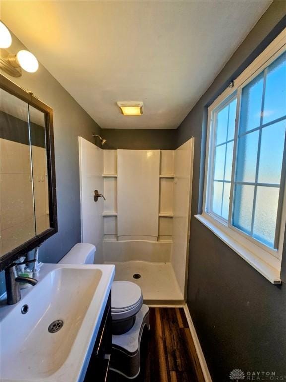 full bath featuring toilet, wood finished floors, vanity, and a walk in shower