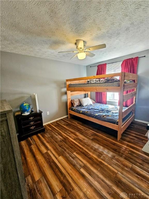 bedroom featuring baseboards, a textured ceiling, wood finished floors, and a ceiling fan