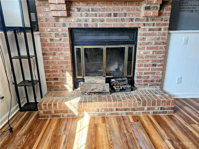 interior details featuring a wainscoted wall, a fireplace, and wood finished floors