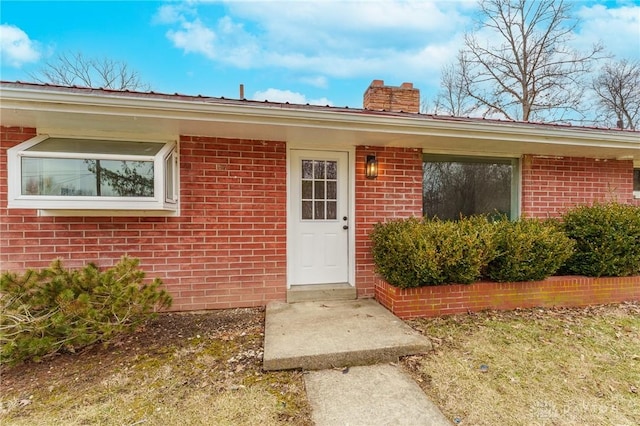 entrance to property with brick siding and a chimney