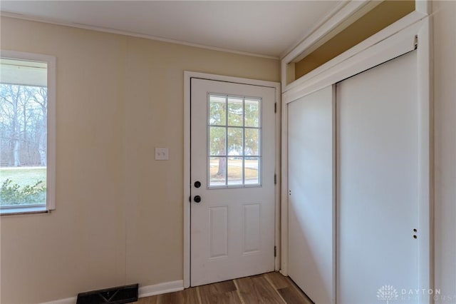 doorway featuring a wealth of natural light, visible vents, wood finished floors, and crown molding