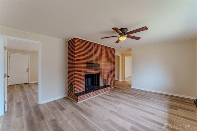 unfurnished living room with a fireplace, baseboards, light wood-style floors, and a ceiling fan