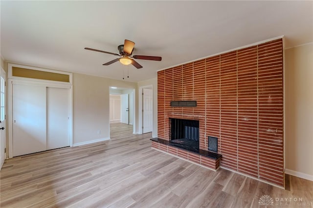 unfurnished living room with baseboards, a fireplace, wood finished floors, and a ceiling fan