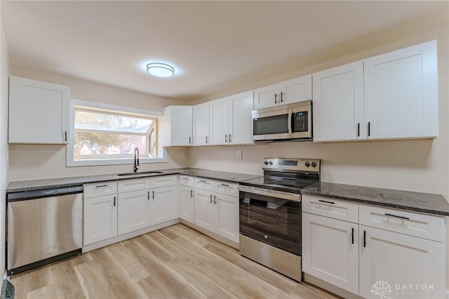 kitchen with a sink, light wood-style flooring, white cabinetry, and stainless steel appliances