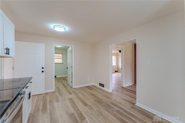 unfurnished dining area featuring light wood finished floors, baseboards, and a ceiling fan