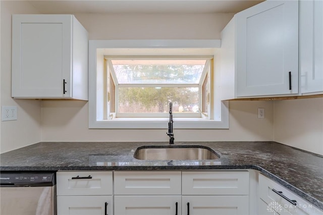 kitchen with a sink, dark stone countertops, white cabinetry, and stainless steel dishwasher