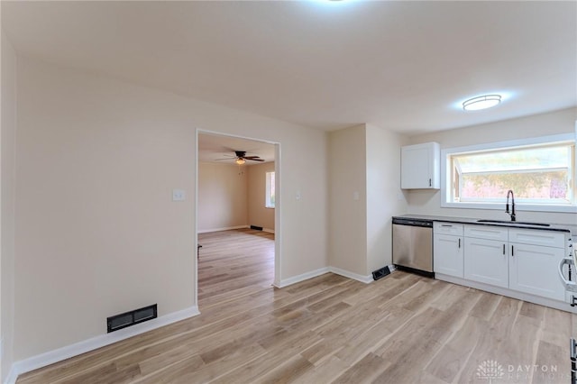 kitchen with dark countertops, visible vents, light wood-style flooring, stainless steel dishwasher, and a sink